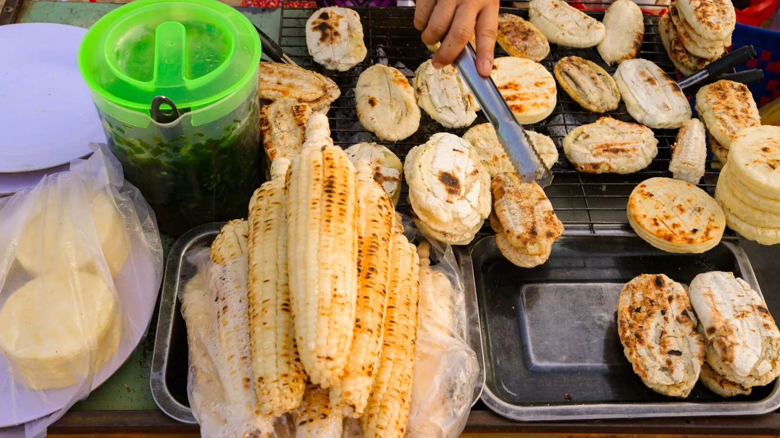Close-up of Vietnamese street food with grilled corn and rice cakes at a local market.