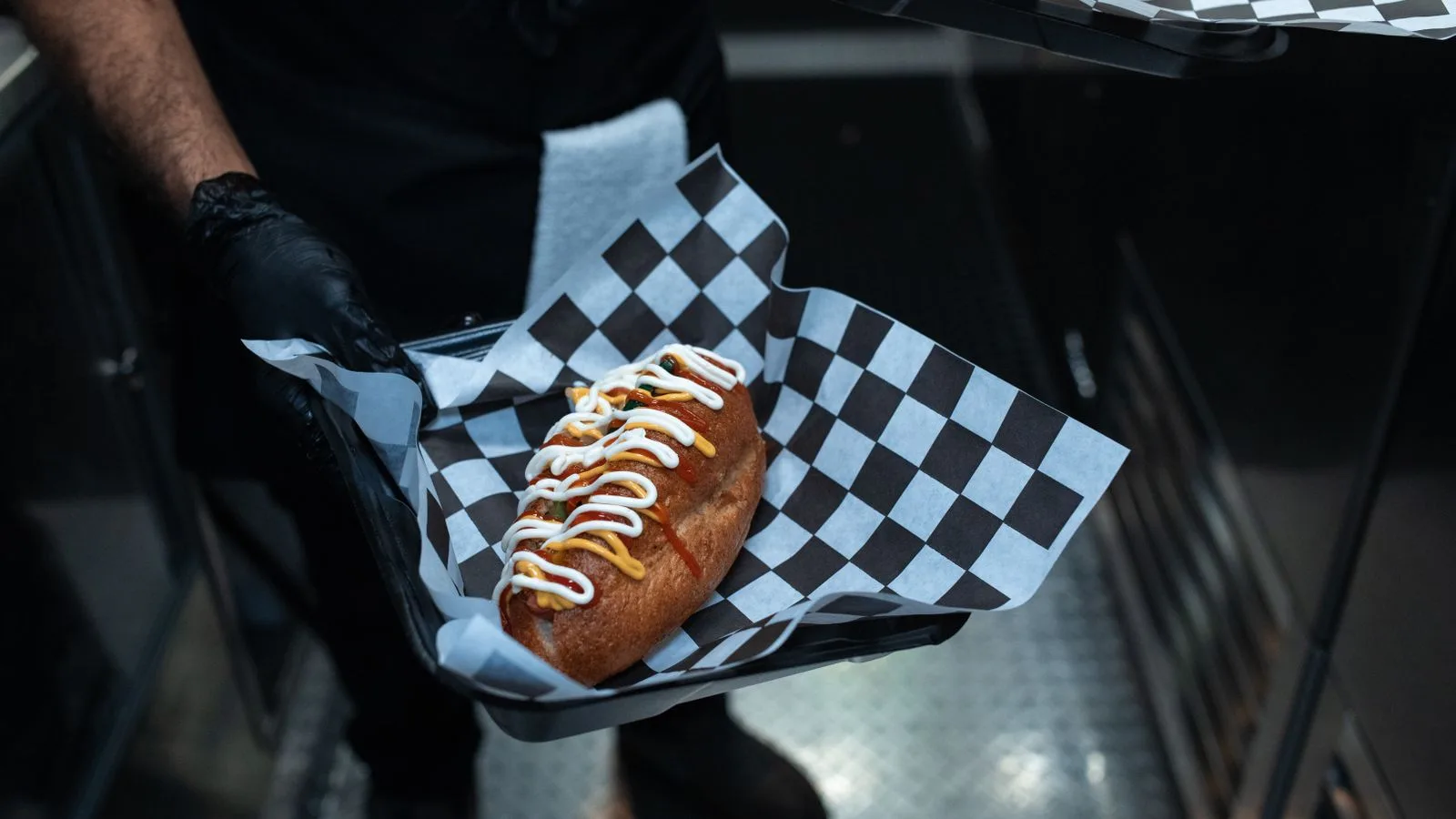 Delicious hot dog with toppings served in a commercial kitchen setting.
