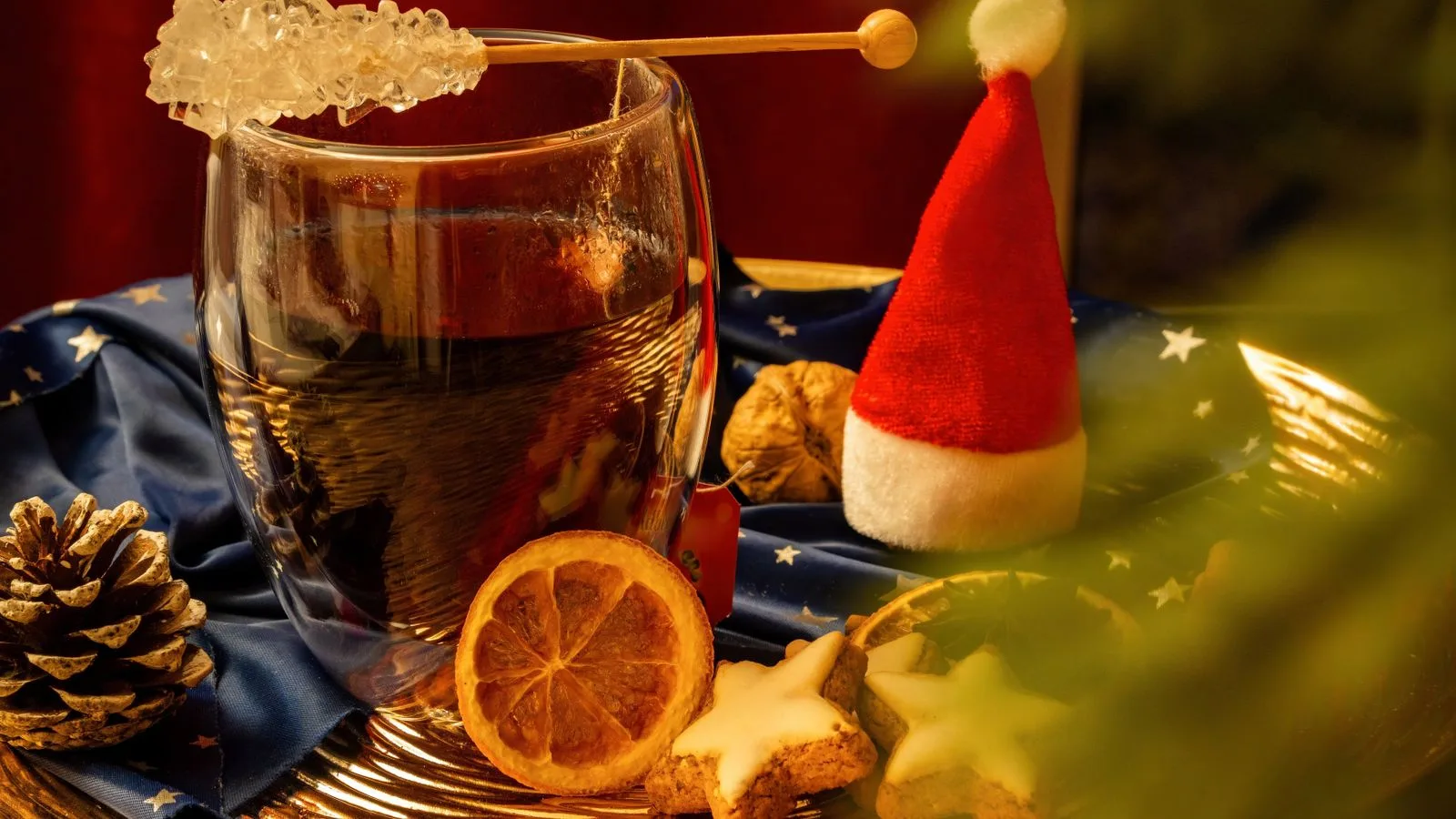 A cozy festive setup featuring mulled wine, star cookies, and seasonal decor on a warm winter evening.