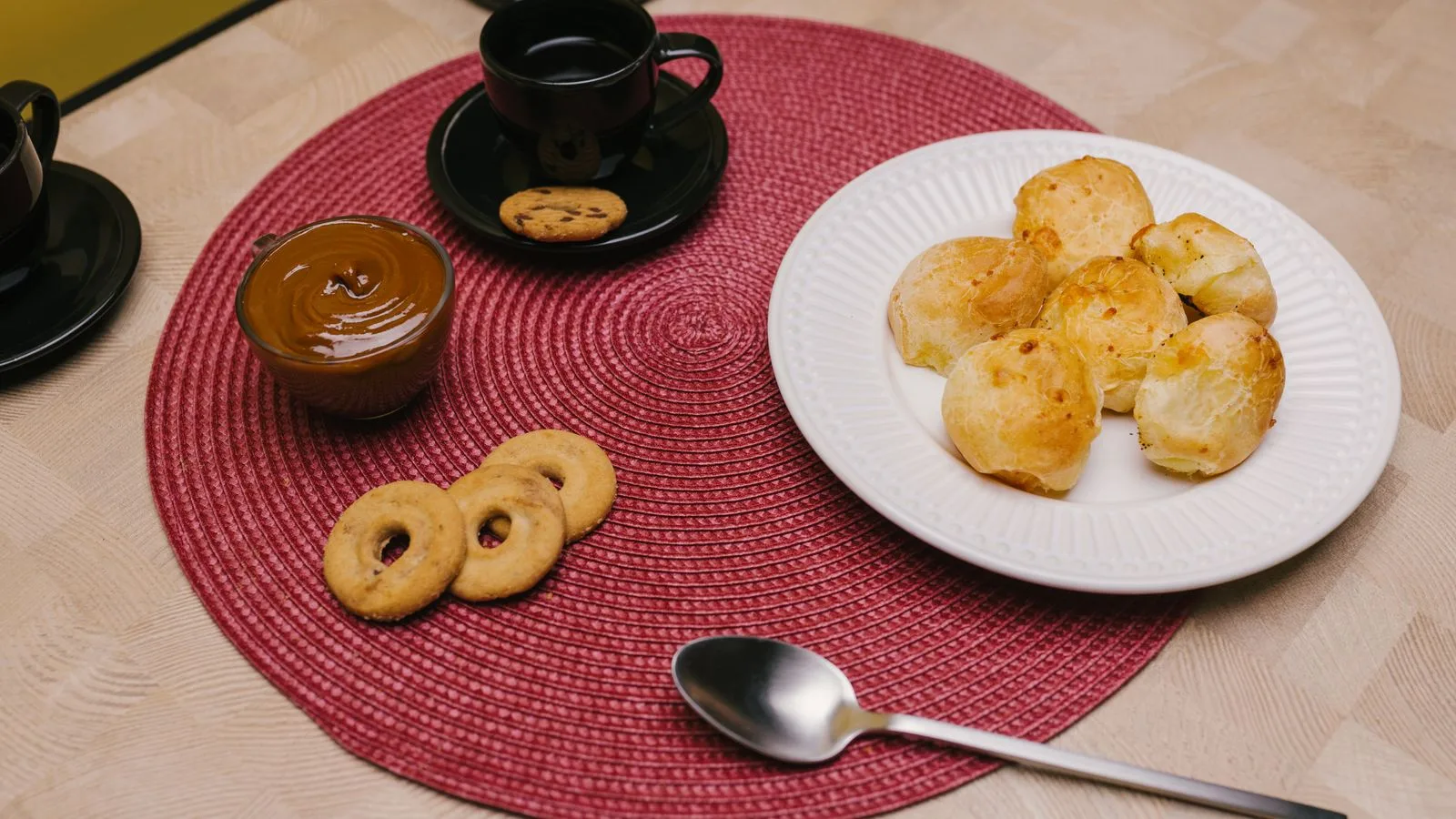 Delicious Brazilian snacks including pão de queijo, coffee, and cookies on a table.