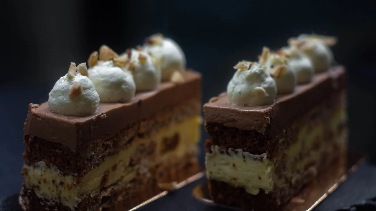 Indulgent chocolate mousse cake slices topped with whipped cream and nuts.