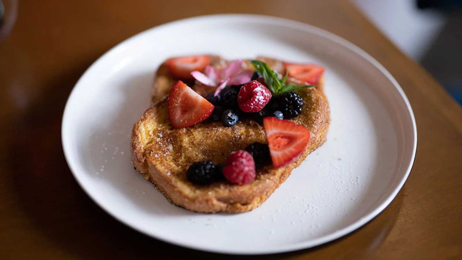 Close-up of French toast topped with strawberries, raspberries, and blackberries on a plate.