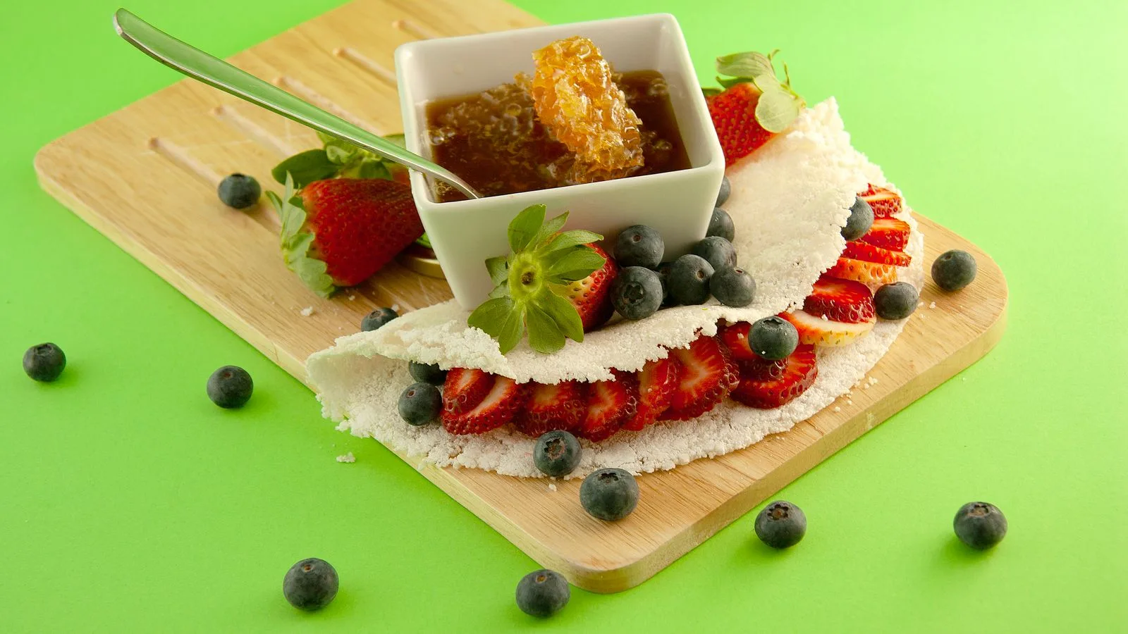 Delicious strawberry and blueberry tapioca on a cutting board with fresh honeycomb.