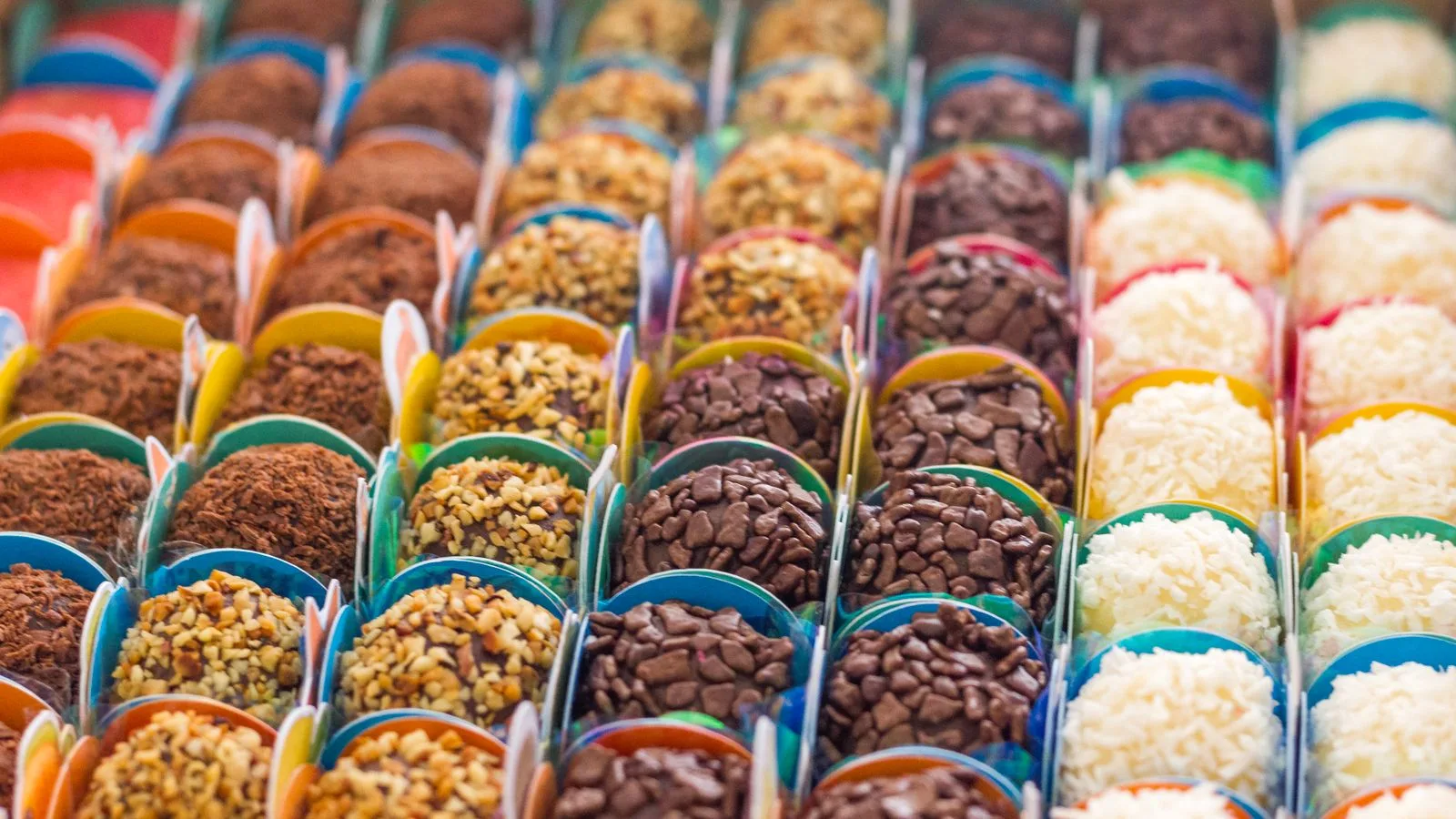 Colorful array of Brazilian brigadeiros covered in sprinkles, nuts, and coconut.