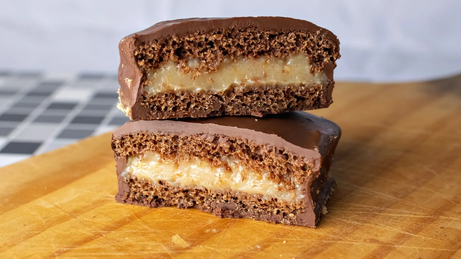 Close-up of freshly baked chocolate caramel slices on a wooden board.