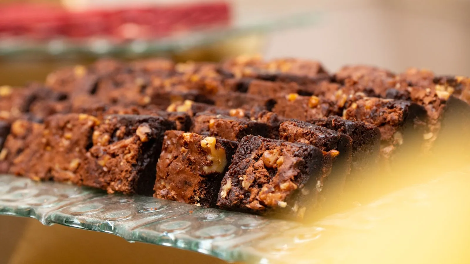 Close-up view of freshly baked chocolate brownies with nuts displayed on a decorative glass tray.