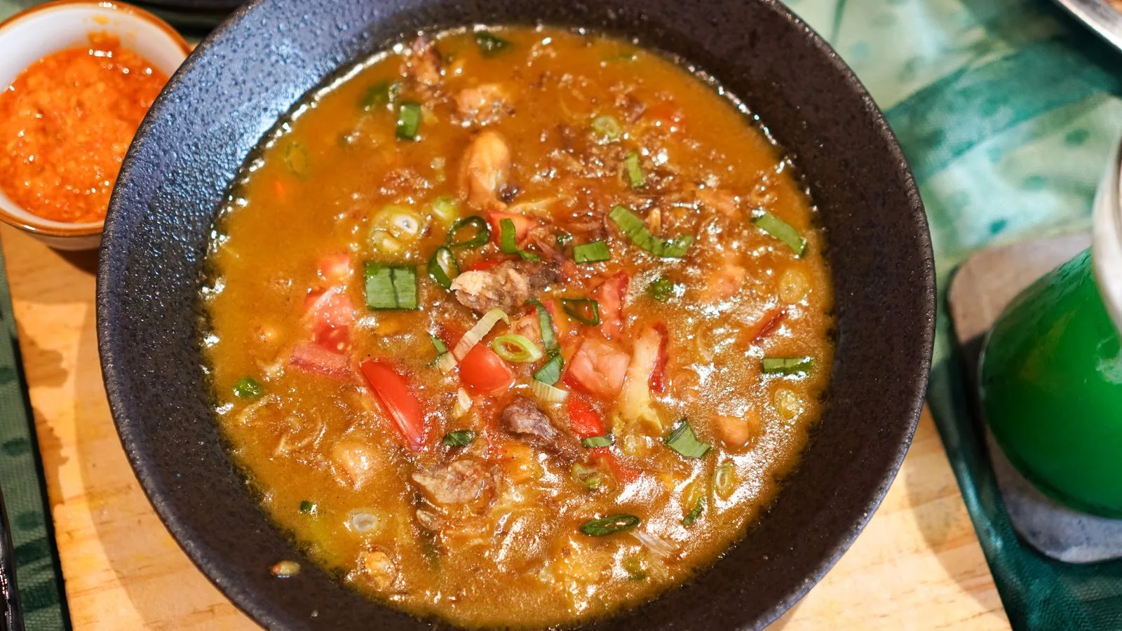 Delicious Indonesian Sop Buntut served with spicy sambal on a wooden table.