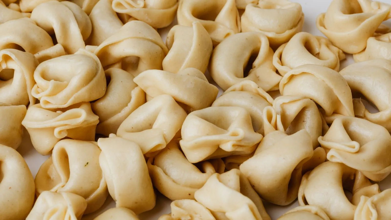 Detailed close-up view of a pile of uncooked homemade tortellini, showcasing Italian culinary tradition.