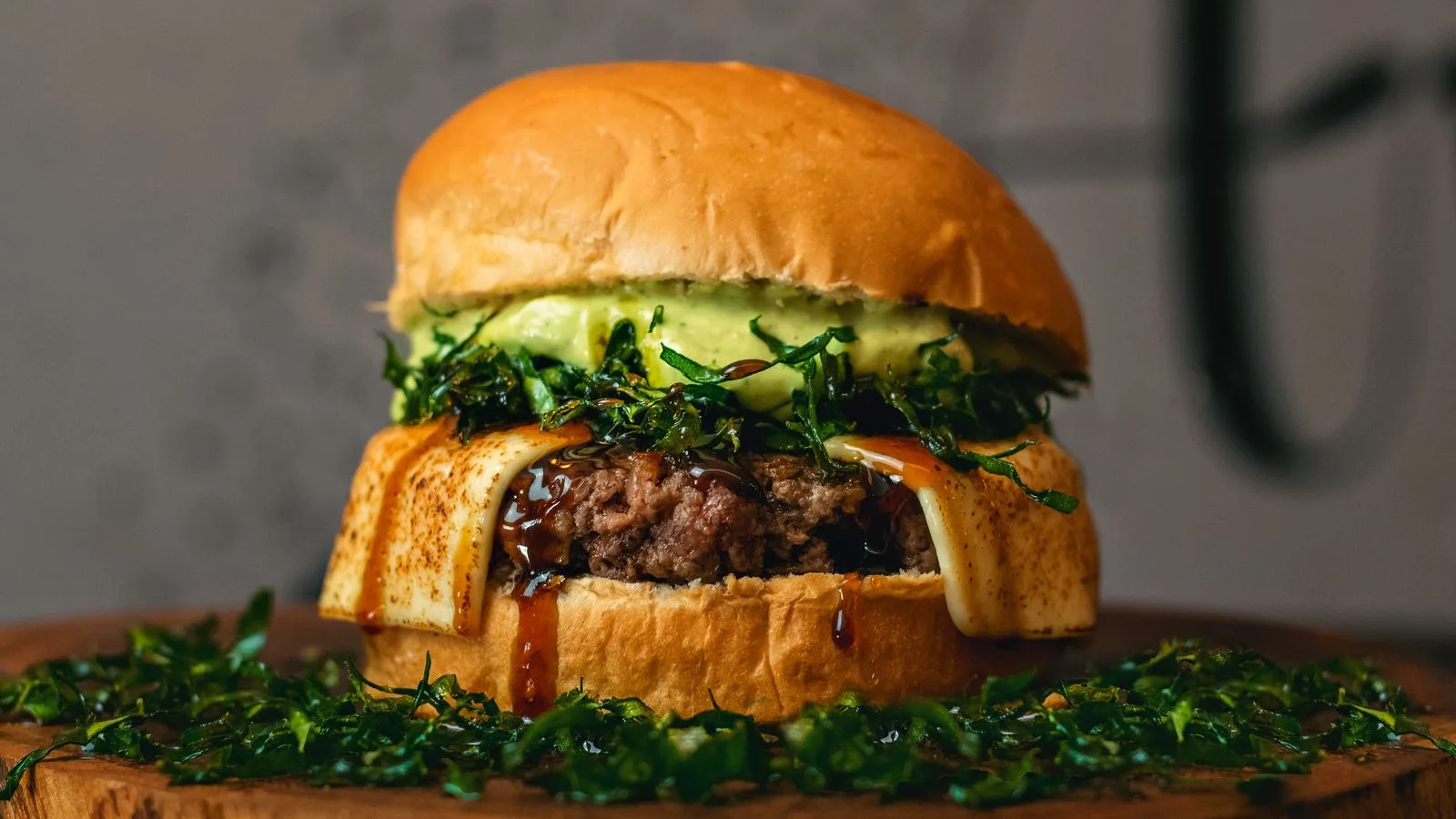 Delicious gourmet burger with cheese and greens on a wooden board. Perfect for food lovers.