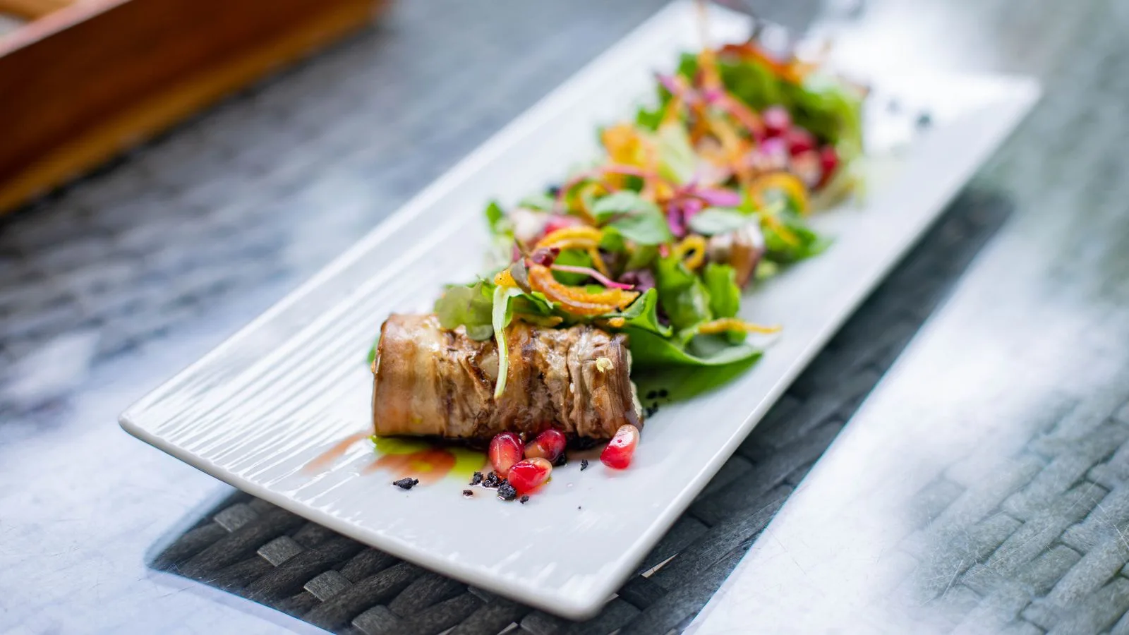 Delicious beef roulade served with a vibrant salad on a rectangular plate, ideal for gourmet food lovers.