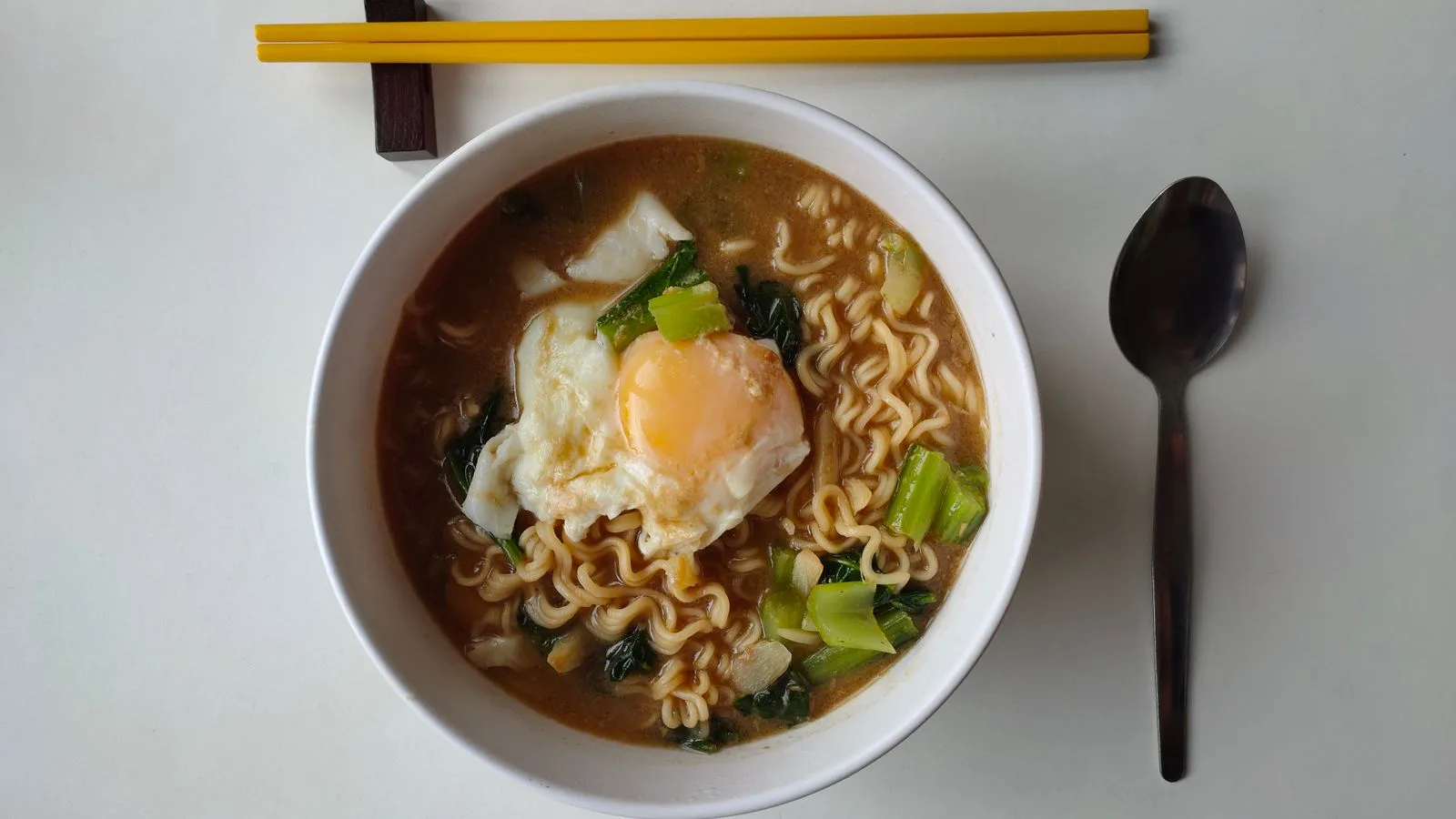Hot ramen noodle soup topped with a poached egg and vegetables, perfect for dinner.