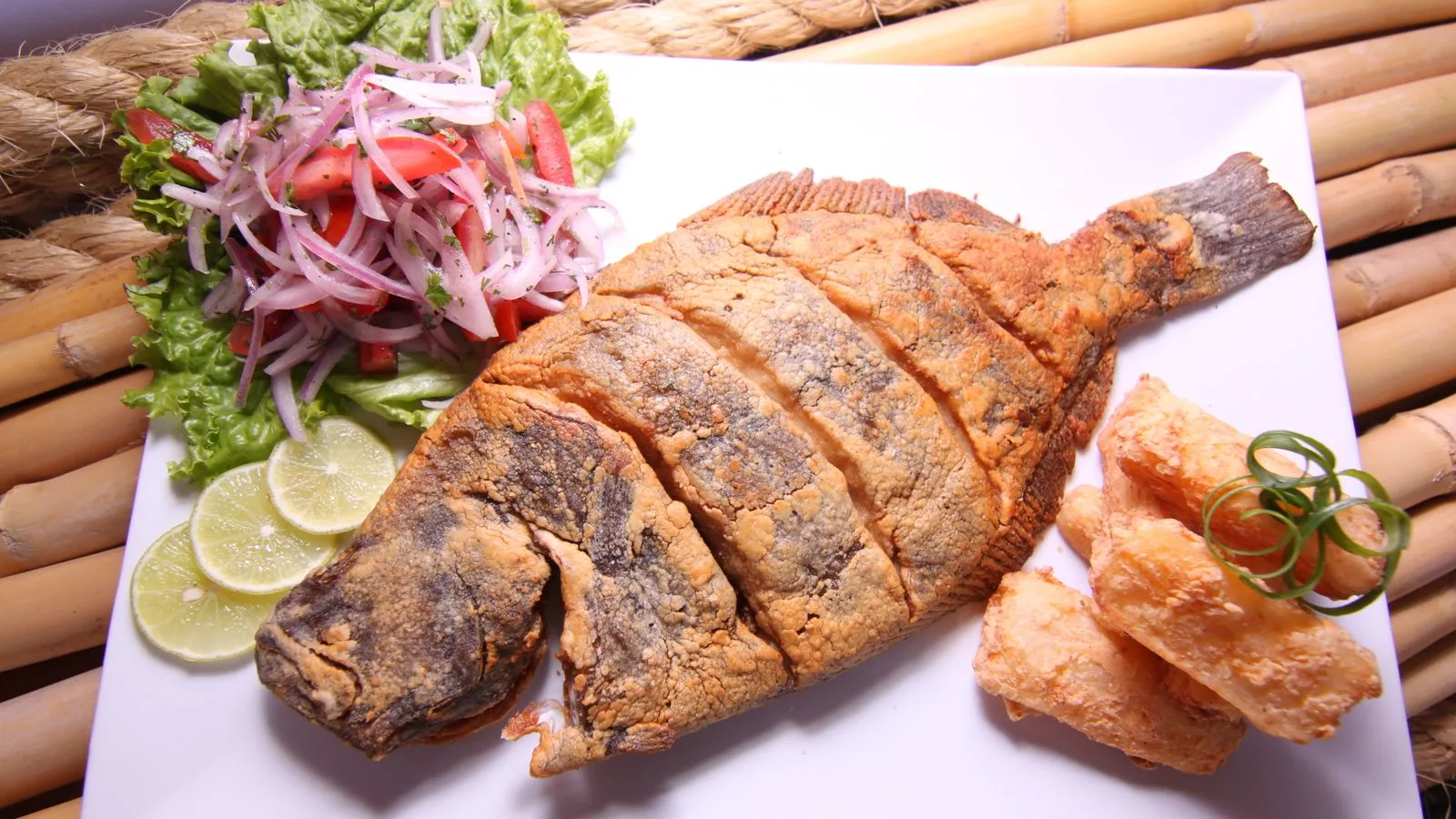Deliciously prepared Peruvian fried fish plated with fresh salad, lime slices, and crispy yuca.
