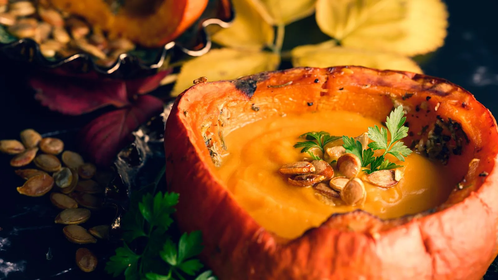 Delicious creamy pumpkin soup served in a pumpkin bowl. Perfect for a hearty autumn dinner.