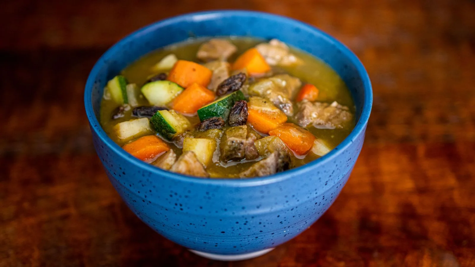 Colorful homemade vegetable stew in a blue bowl, perfect for healthy eating.