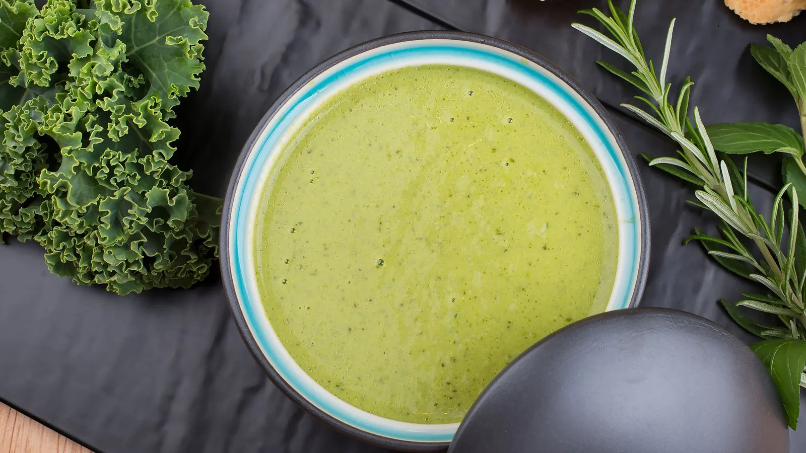 A flavorful green soup garnished with fresh kale and herbs, perfect for a healthy meal.