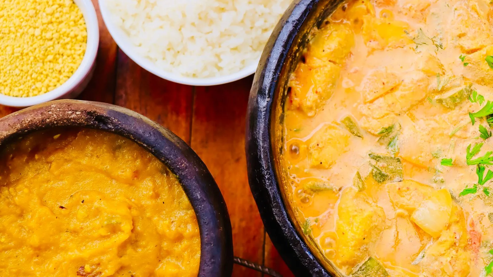 Colorful Brazilian Moqueca with sides on wooden table. Perfect for culinary and cultural themes.