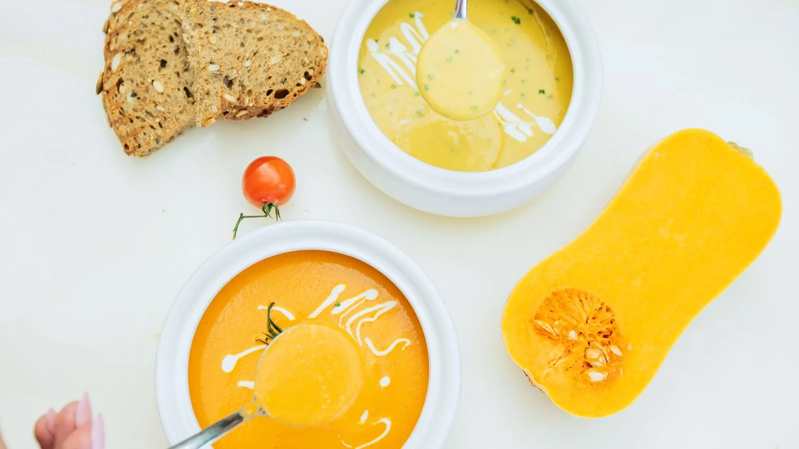 Delicious pumpkin soup served with sliced bread and cherry tomato. Perfect for a cozy meal.