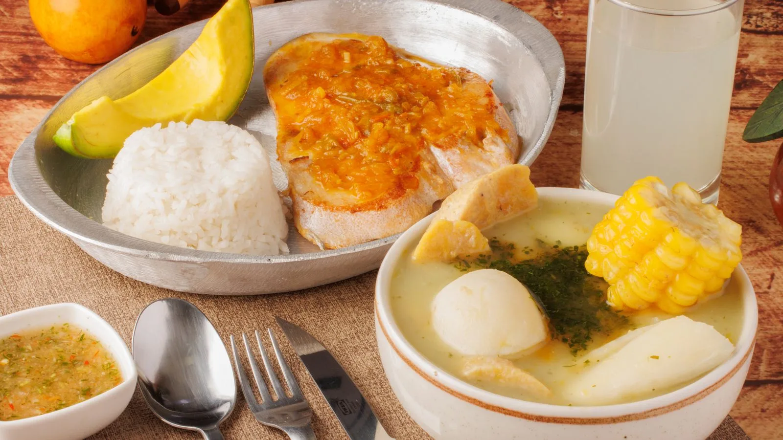 Delight in a traditional Colombian meal featuring ajiaco soup, rice, avocado, and tamarind juice.