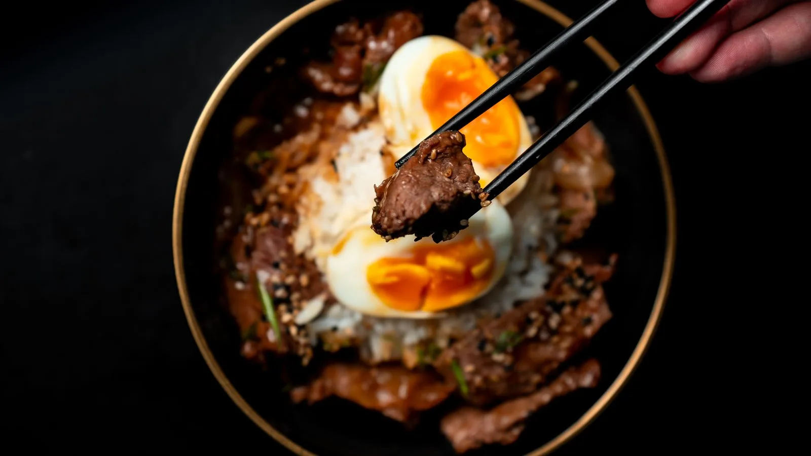 Close-up of a flavorful Asian beef dish with soft-boiled egg and rice, perfect for a gourmet meal.