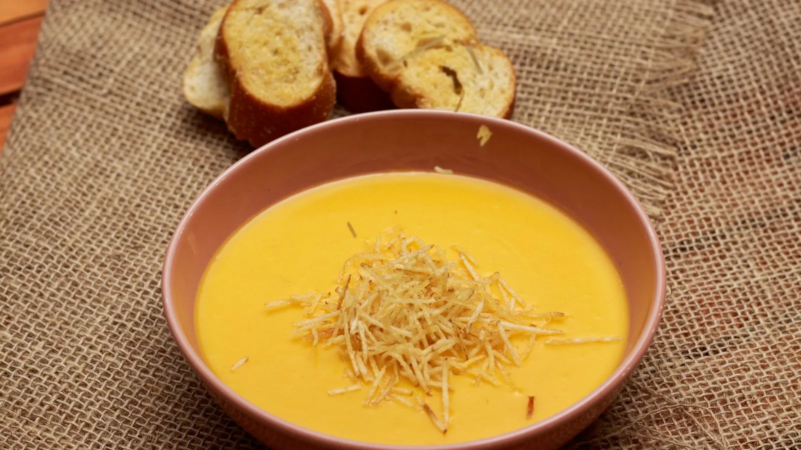 Delicious creamy pumpkin soup served with crispy bread slices in a rustic setting.