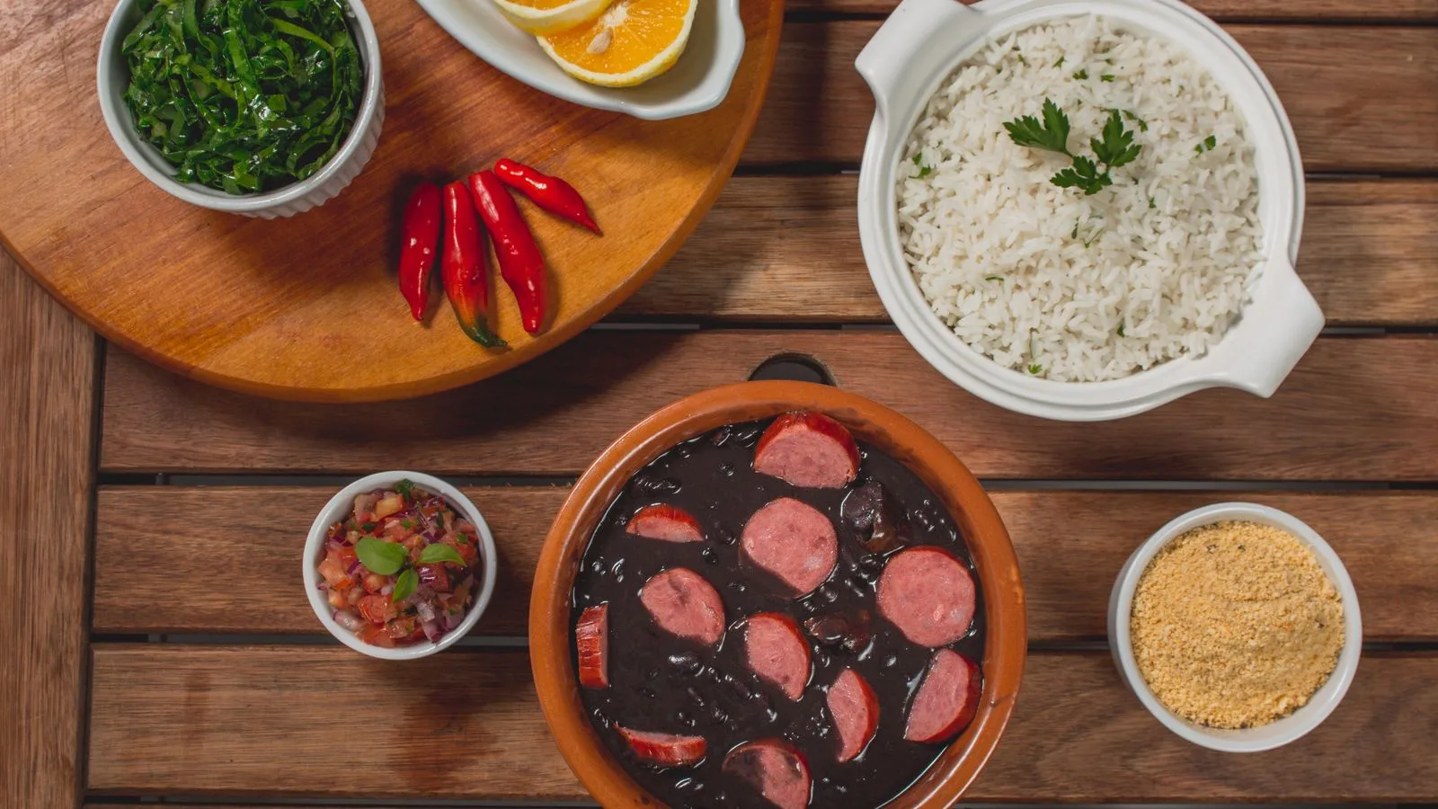 Traditional Brazilian feijoada served with rice, greens, and orange slices, perfect for a hearty meal.