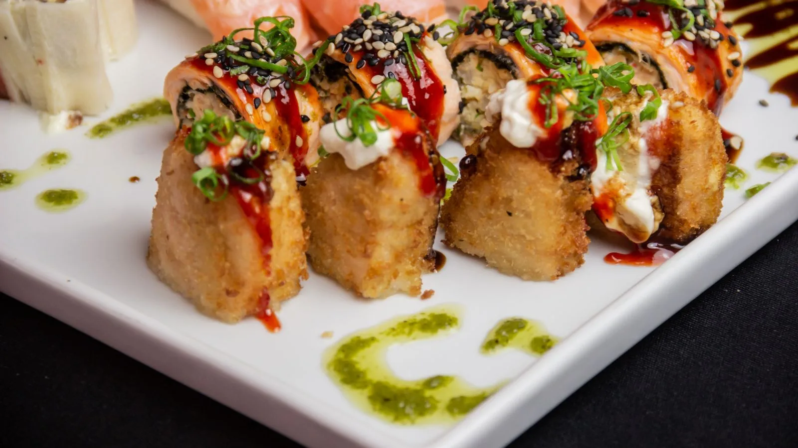 Close-up of a vibrant sushi platter showcasing a mix of textures and flavors, garnished with sesame seeds and sauce.