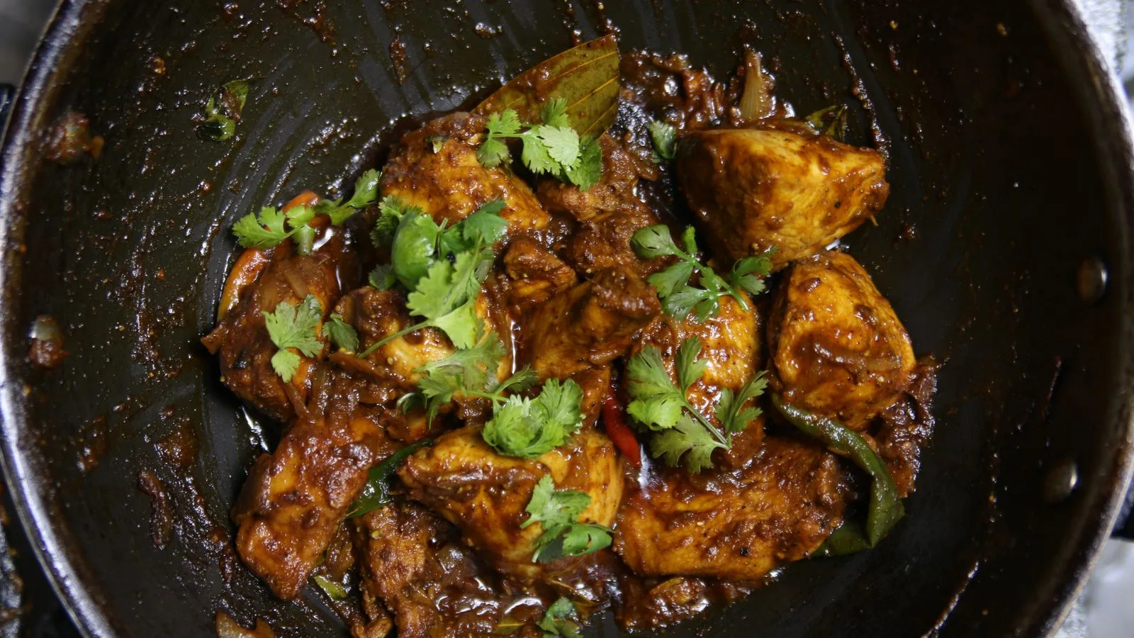 Close-up of spicy Indian chicken curry garnished with cilantro.