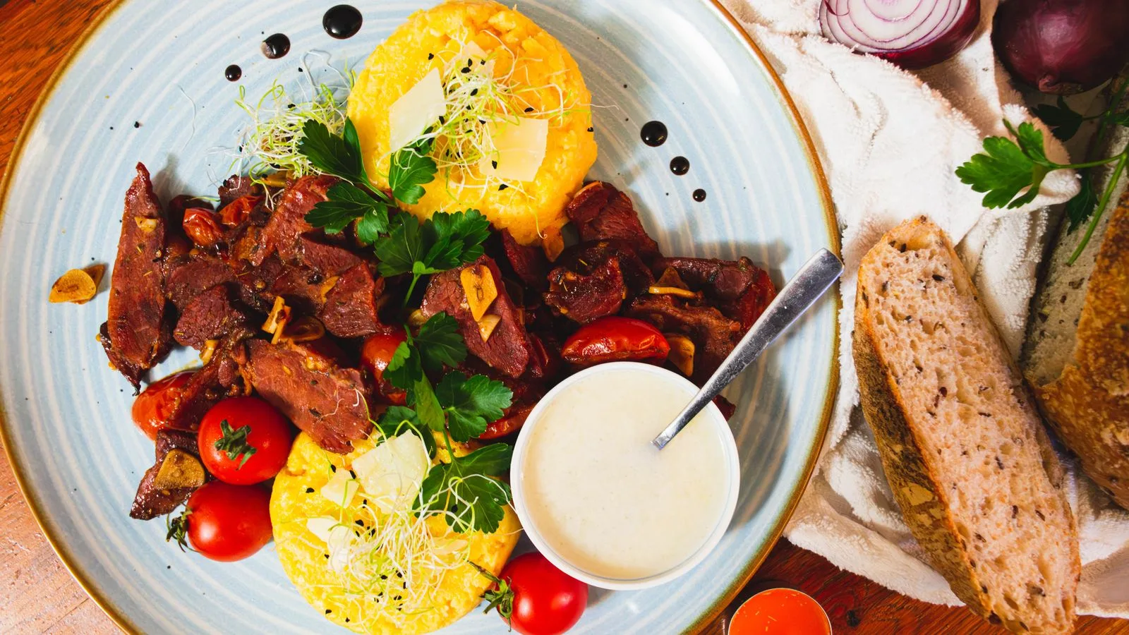 A vibrant dish of polenta, beef, and fresh vegetables, showcasing Romanian flavors.