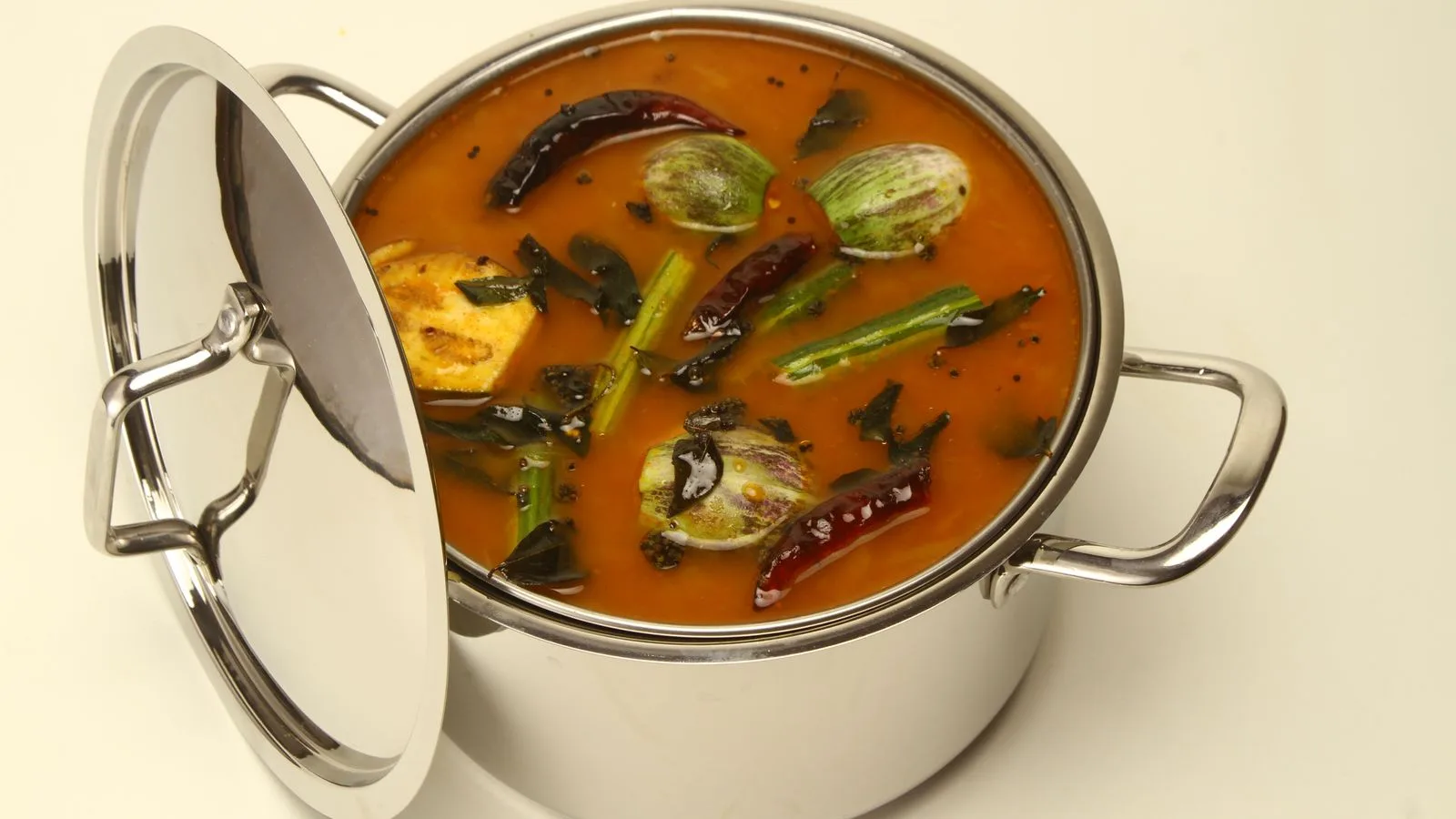 Delicious South Indian sambar in a stainless steel pot with vegetables and spices.