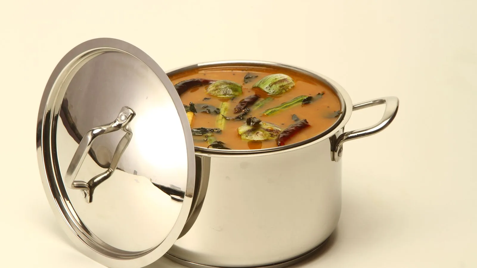 Delicious South Indian sambar curry in a stainless steel pot with colorful vegetables.