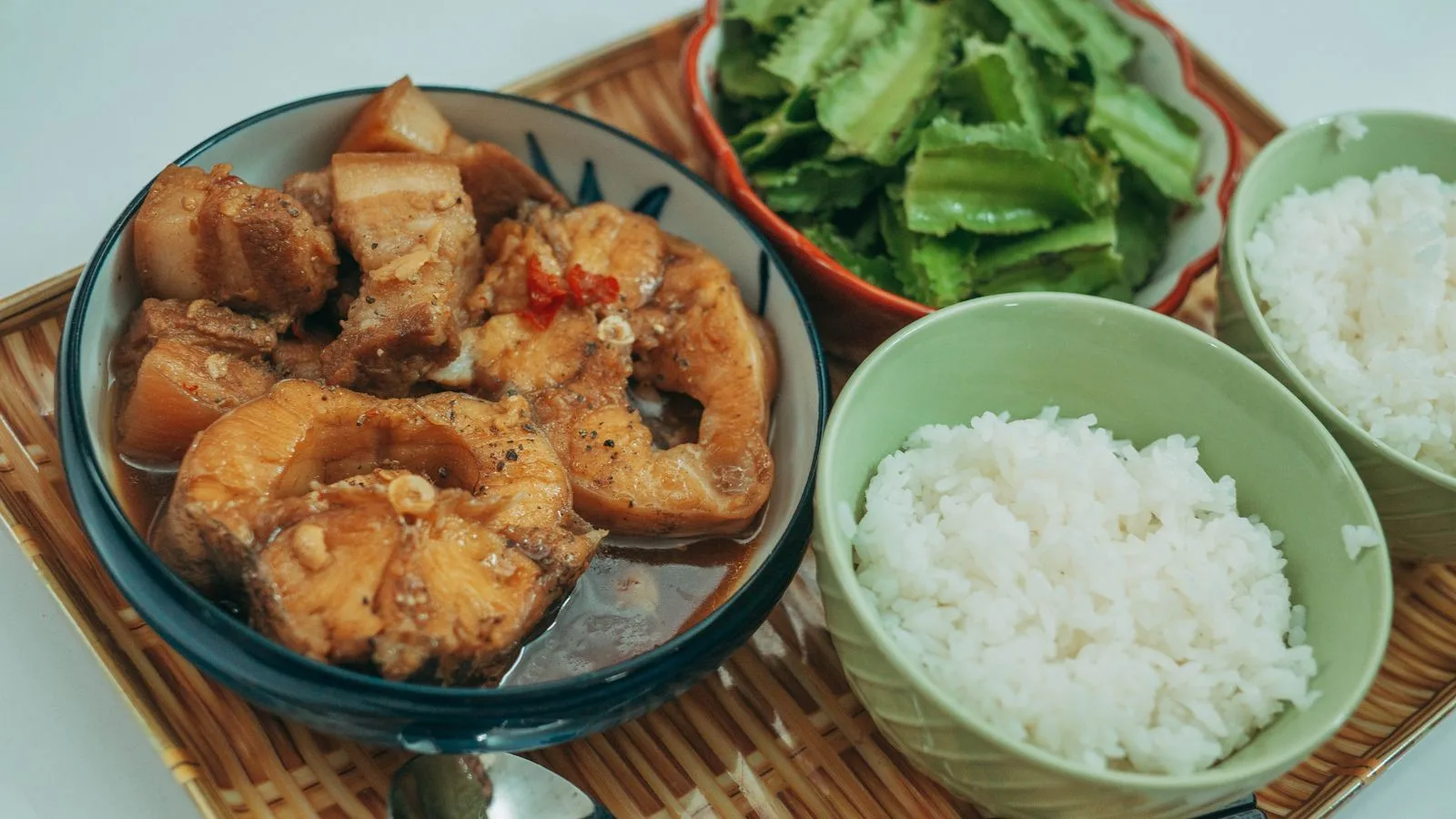 Savor a traditional Asian meal featuring fish stew, steamed rice, and fresh vegetables.