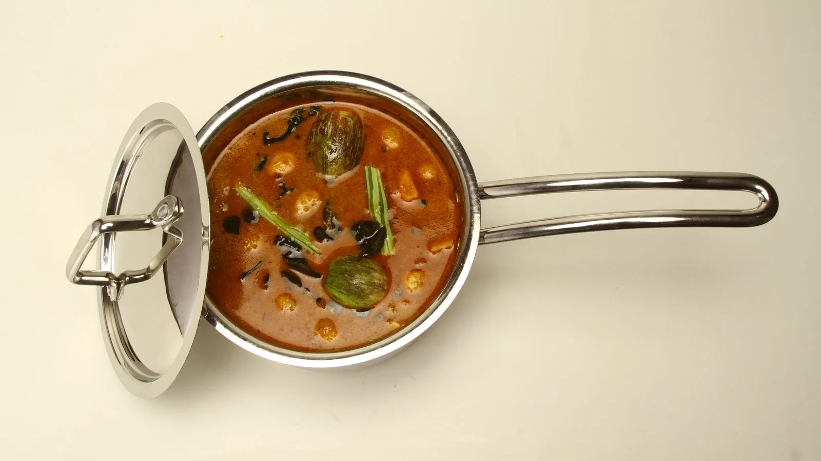 A delicious Indian curry in a stainless steel pot with lid, showcasing vibrant colors and textures.