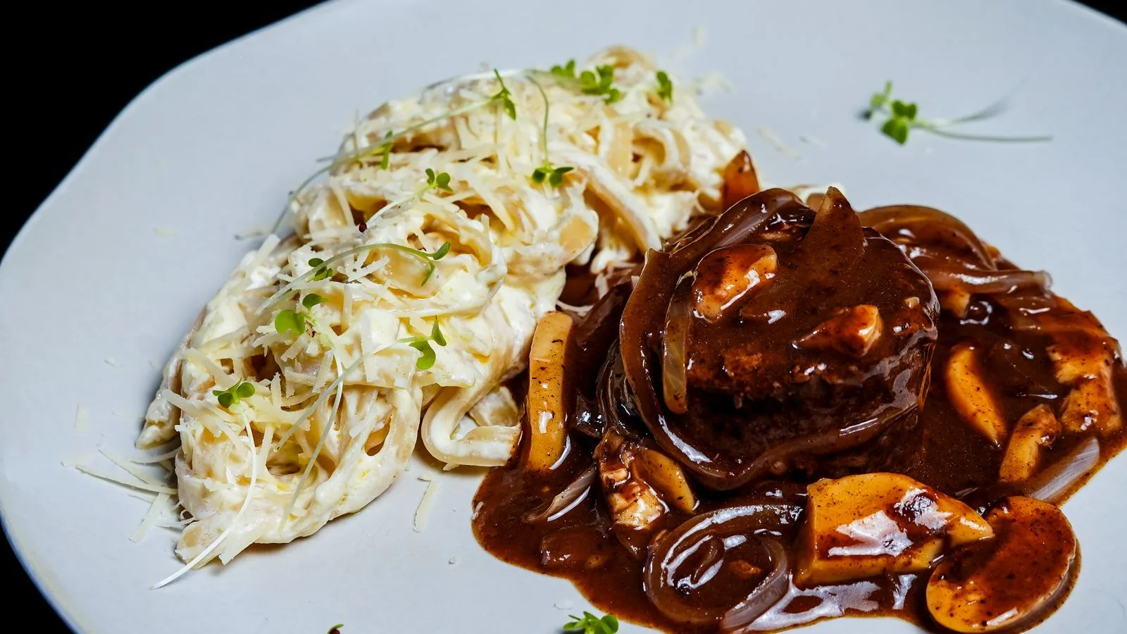Delicious plate of creamy fettuccine alfredo paired with tender beef steak and rich mushroom sauce.