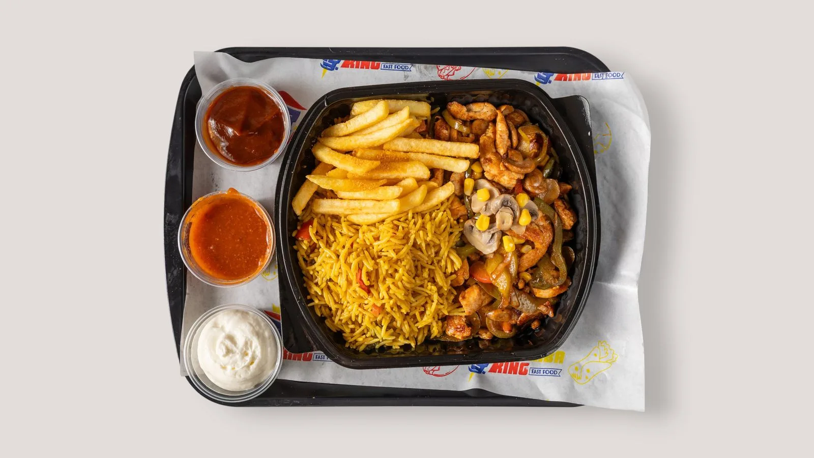 Savor a tasty fast food tray featuring fries, rice, chicken, and sauces.