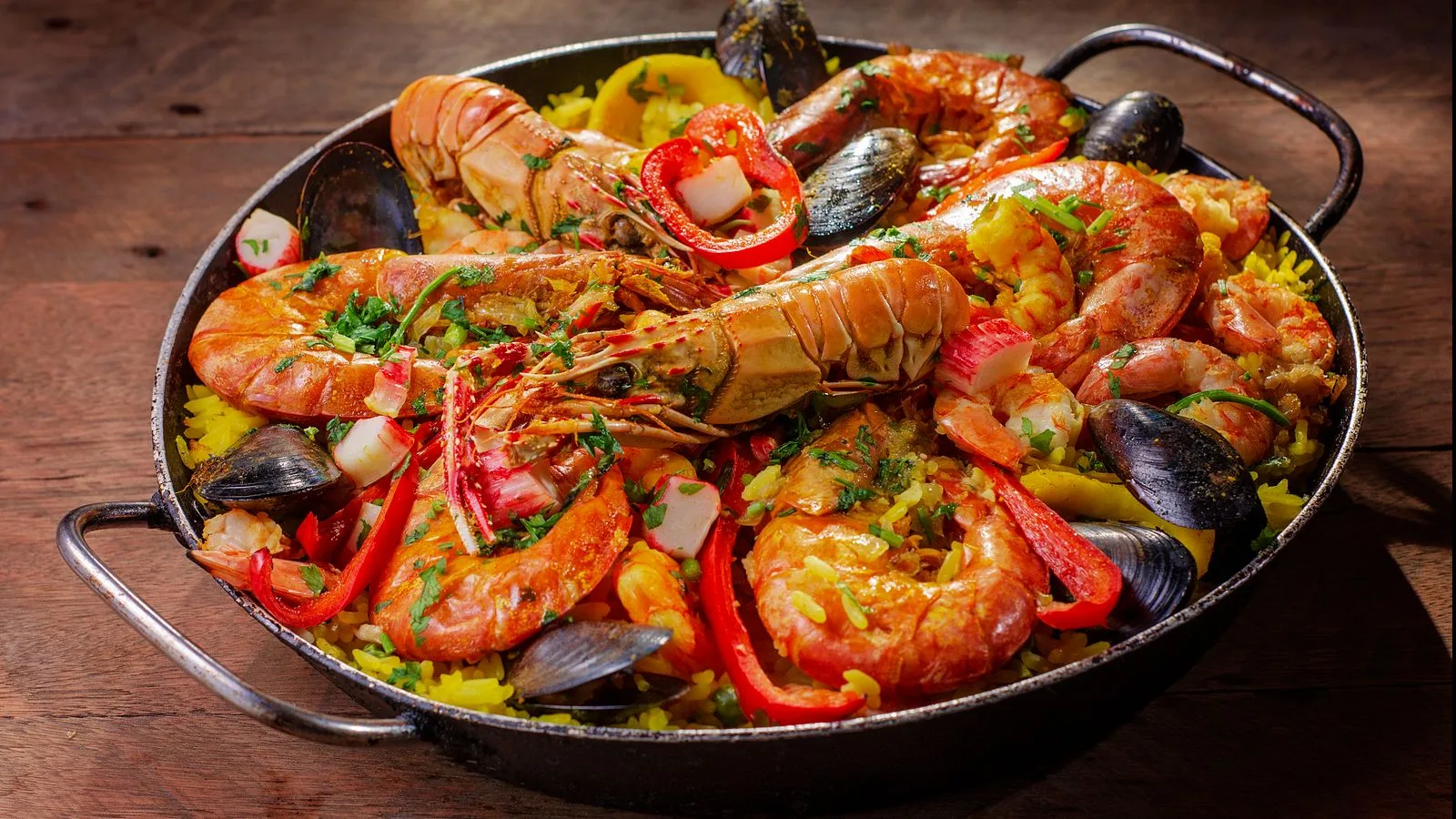 A vibrant and flavorful seafood paella served in a pan with mussels and shrimp.