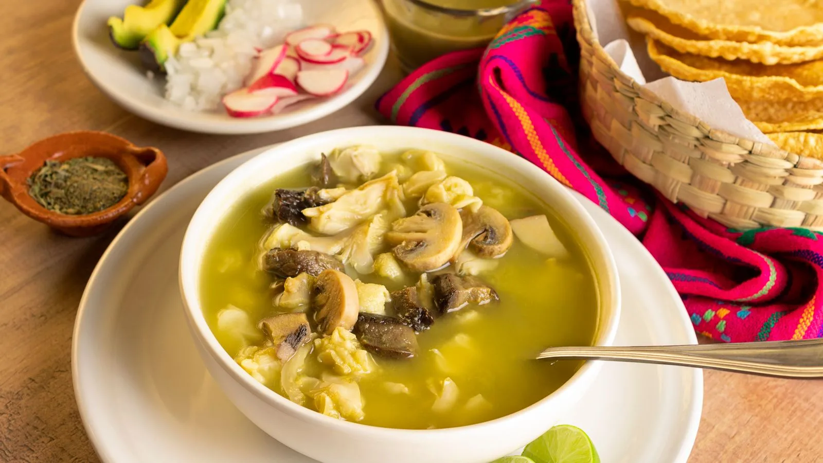 Delicious Mexican mushroom soup served with fresh garnishes, lime, and tortilla chips.