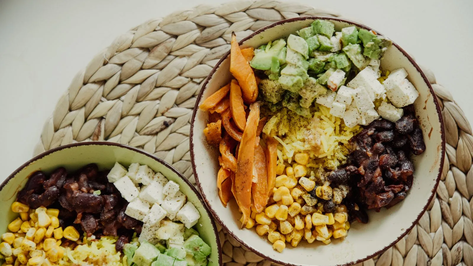 Top view of vegetarian bowls with avocado, corn, beans, and cheese for a delicious meal.