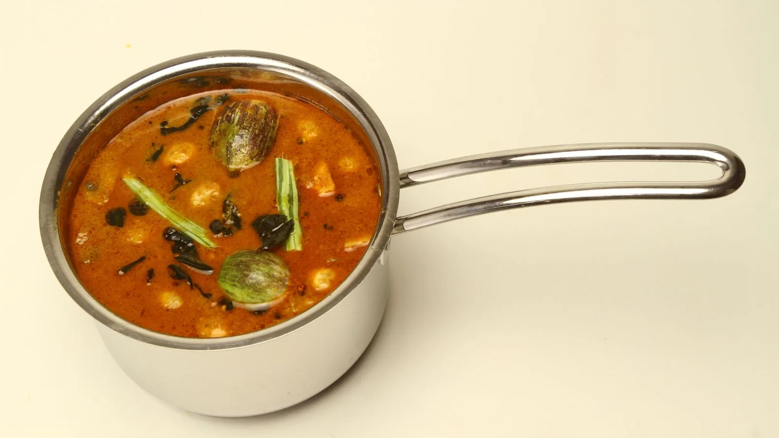 Delicious South Indian sambar with drumstick and eggplant in a stainless steel pot.