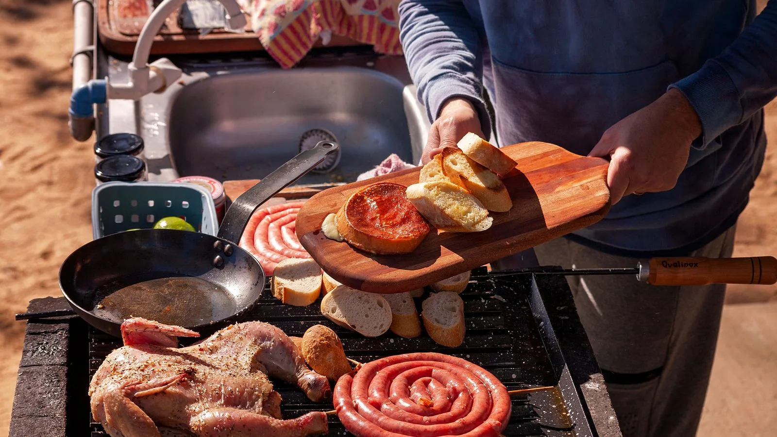 A close-up of a person grilling sausages, chicken, and bread outdoors, creating a delicious summer barbecue.