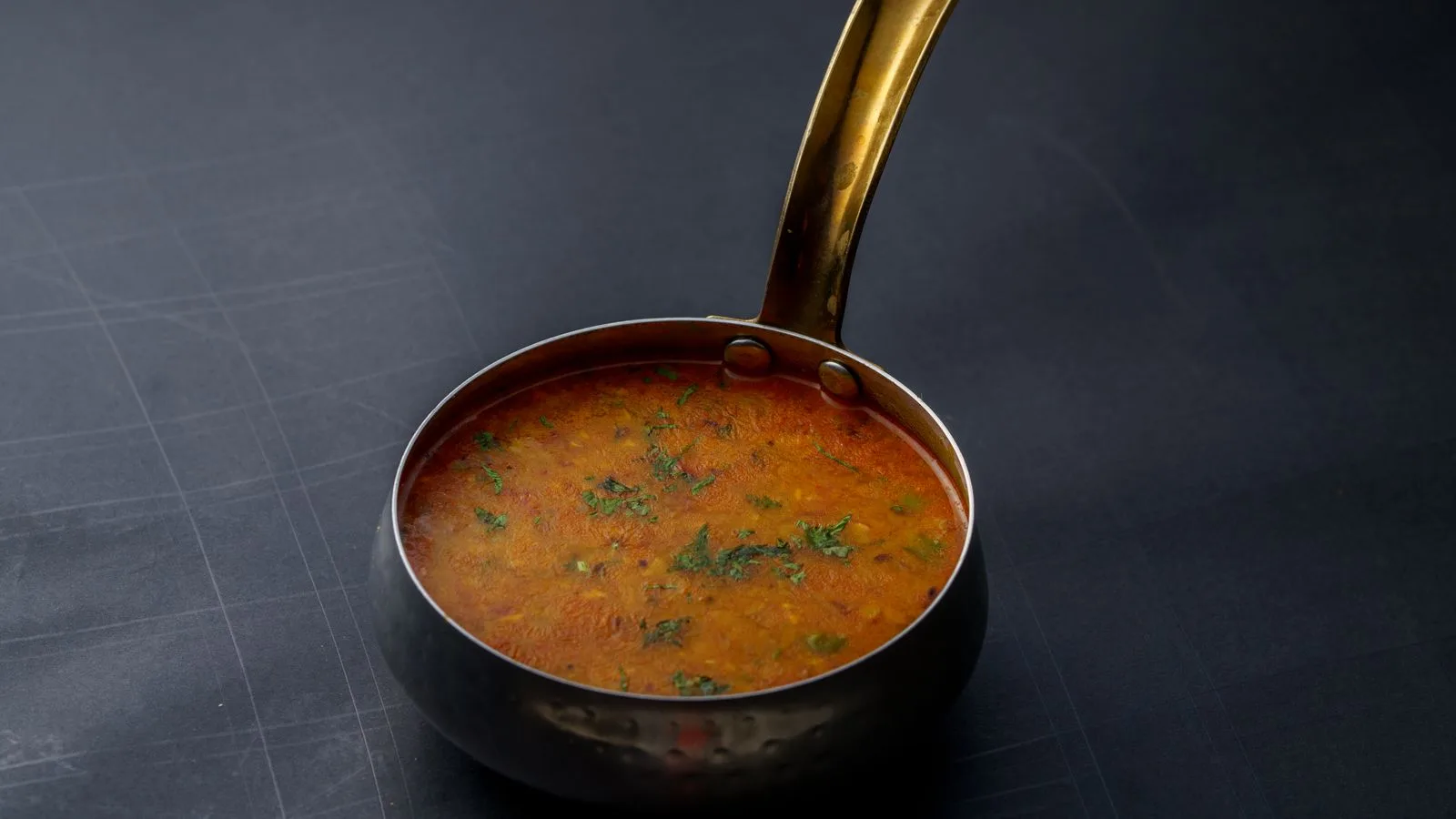 A close-up shot of Indian dal garnished with herbs in a copper pot, offering a taste of traditional cuisine.