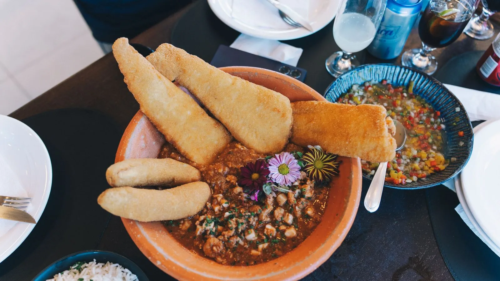 A mouthwatering seafood stew with fried fish and vegetables served in a rustic setting.