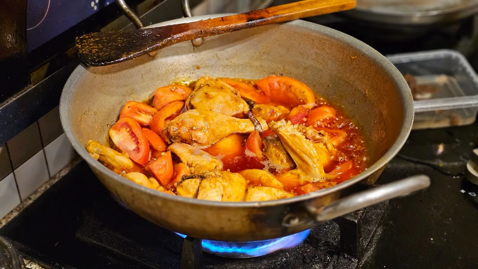 Hearty chicken and tomatoes simmering in a pot on the stove, ideal for cooking themes.