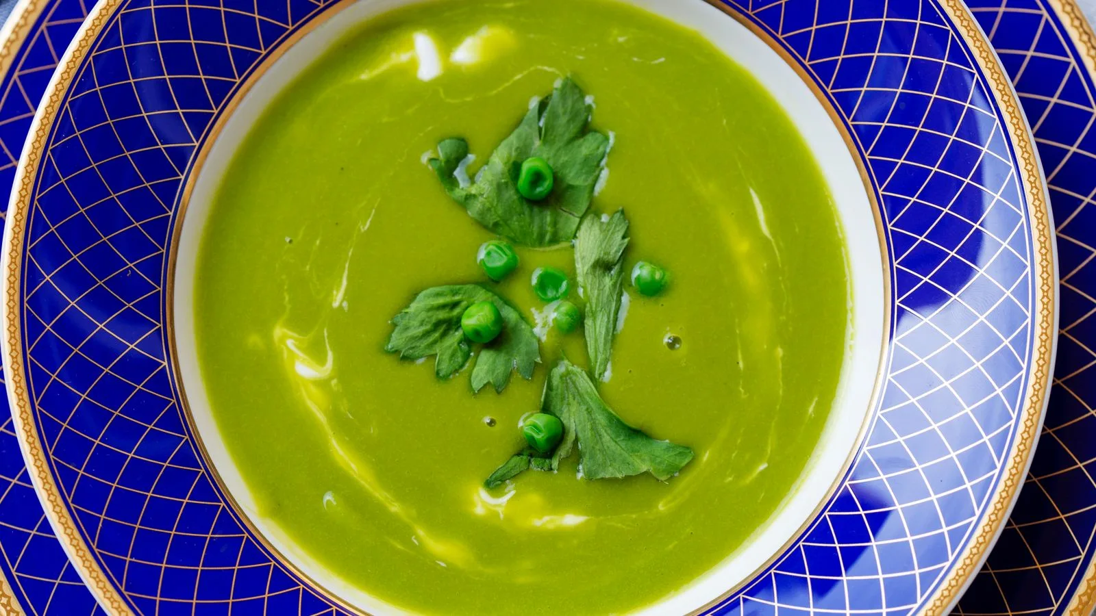 A vibrant green pea soup garnished with parsley on a stylish plate, perfect for gourmet presentations.