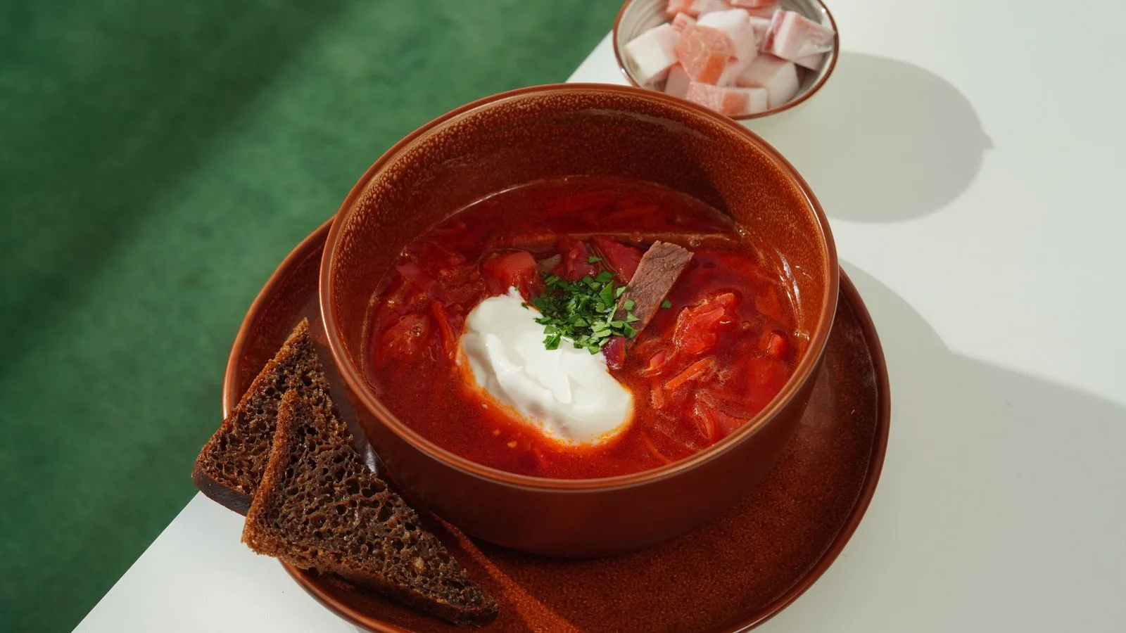 A flavorful bowl of borscht with sour cream and rye bread, perfect for any meal.
