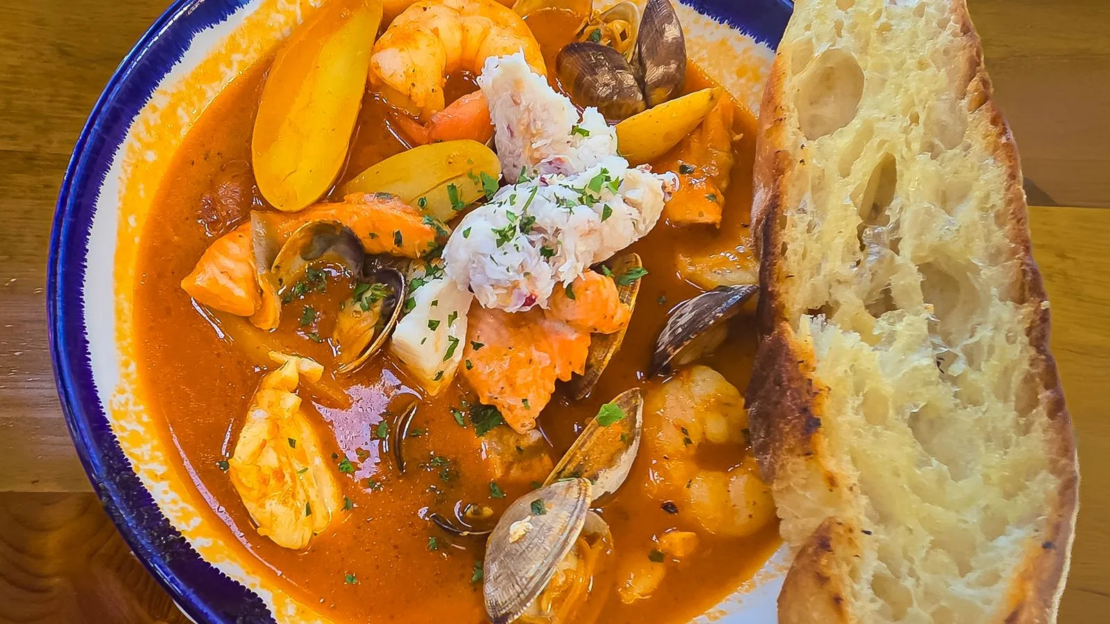 Vibrant seafood stew with assorted seafood and fresh garlic bread, perfect for a hearty meal.