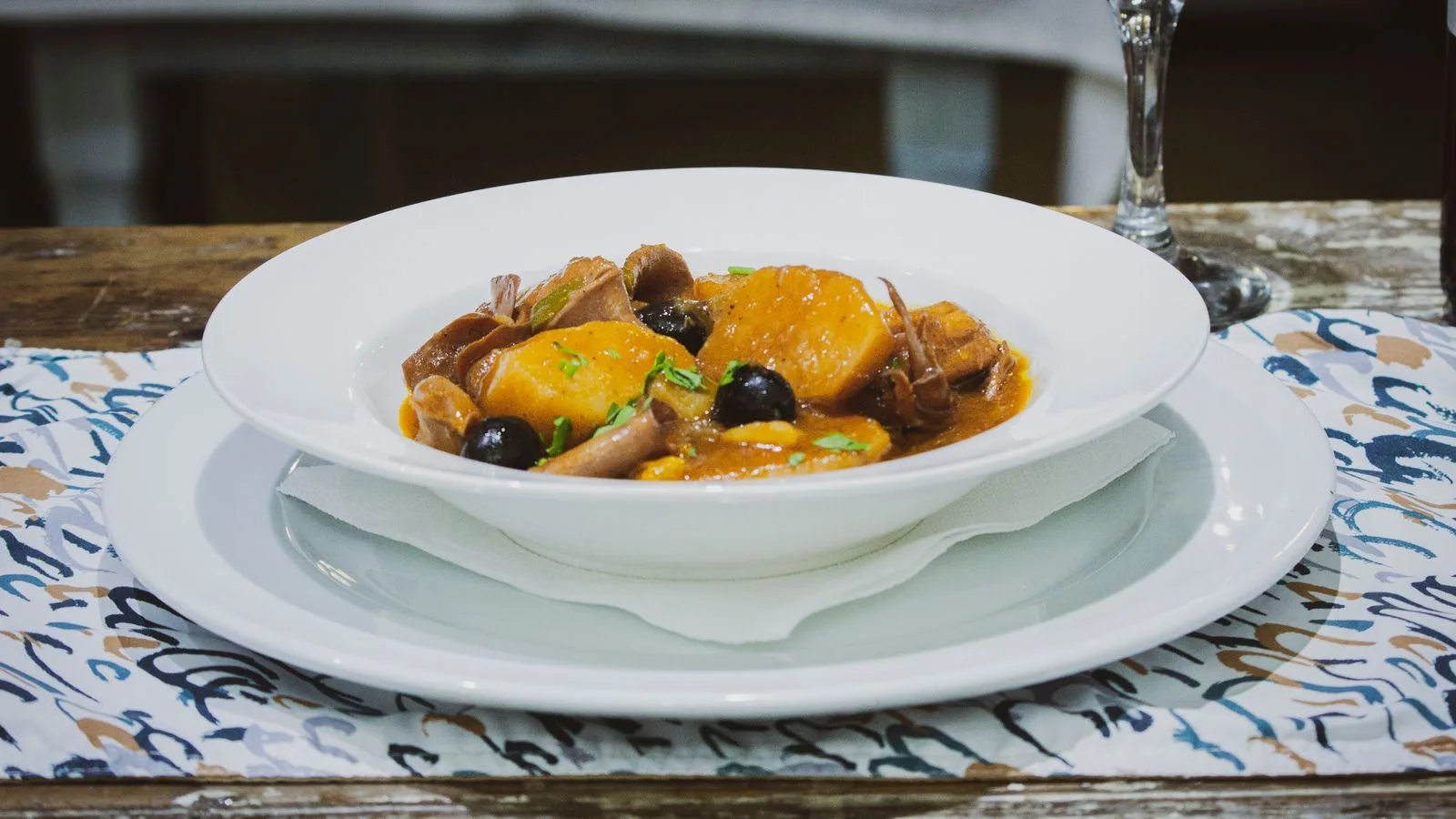 Delicious traditional Angolan stew featuring root vegetables and dark olives in a white bowl.