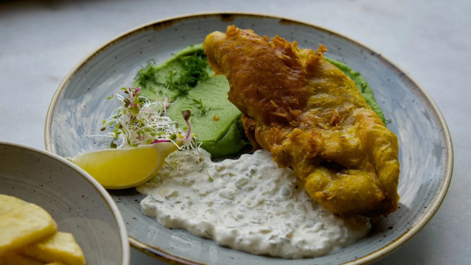 Tasty fish and chips served with tartar sauce and mushy peas.