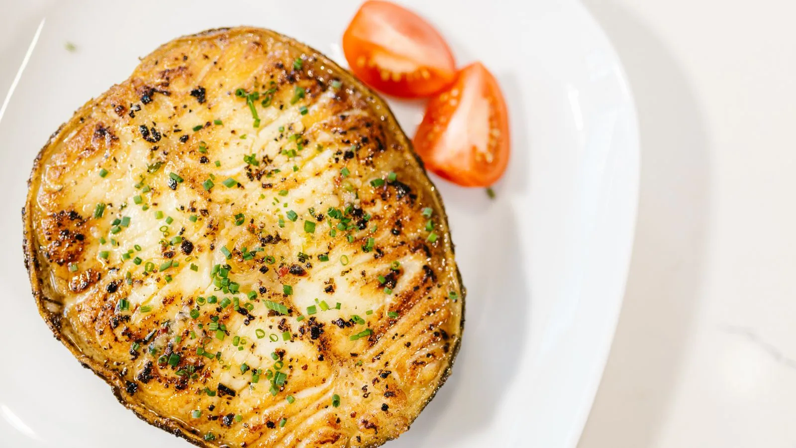 Delicious grilled eggplant seasoned with herbs alongside fresh sliced tomatoes.