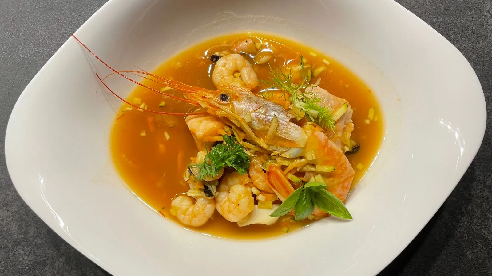 A vibrant seafood soup featuring fresh shrimps and fish in a rich broth.