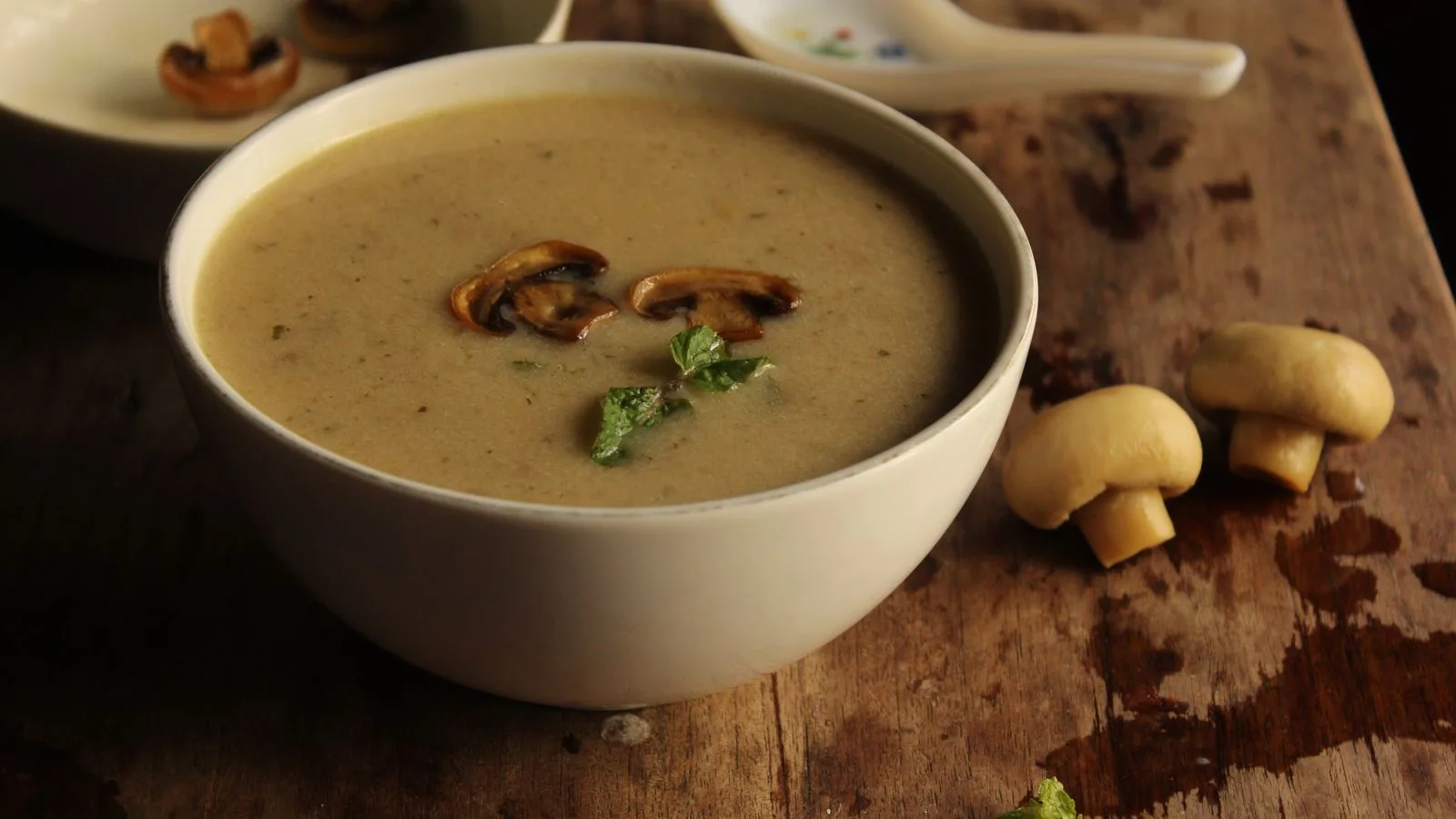 Warm and creamy mushroom soup garnished with mushrooms and herbs in a rustic bowl.